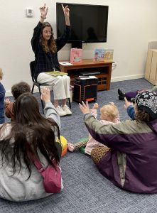 Library staff, children, and parents participate in action rhyme and song.