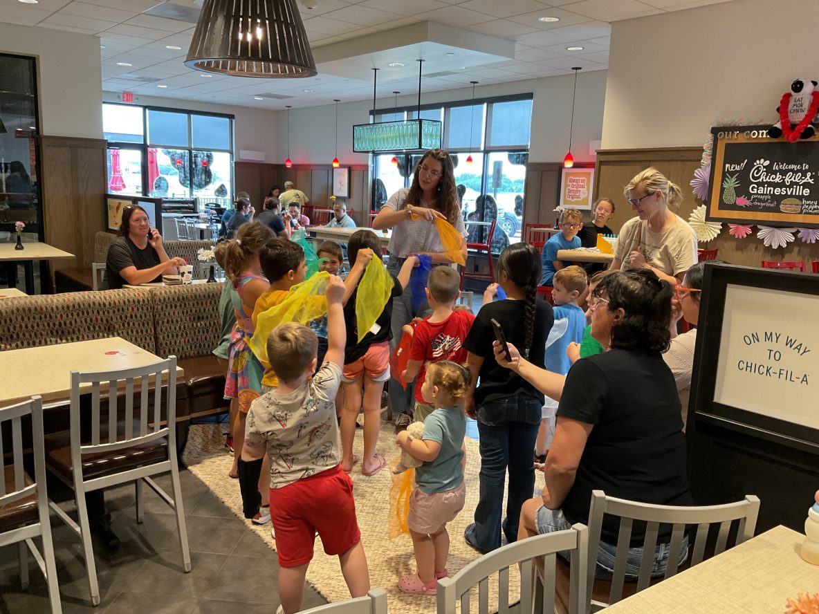 image of a librarian and group of young children waving scarves as they sing at chick-fil-a
