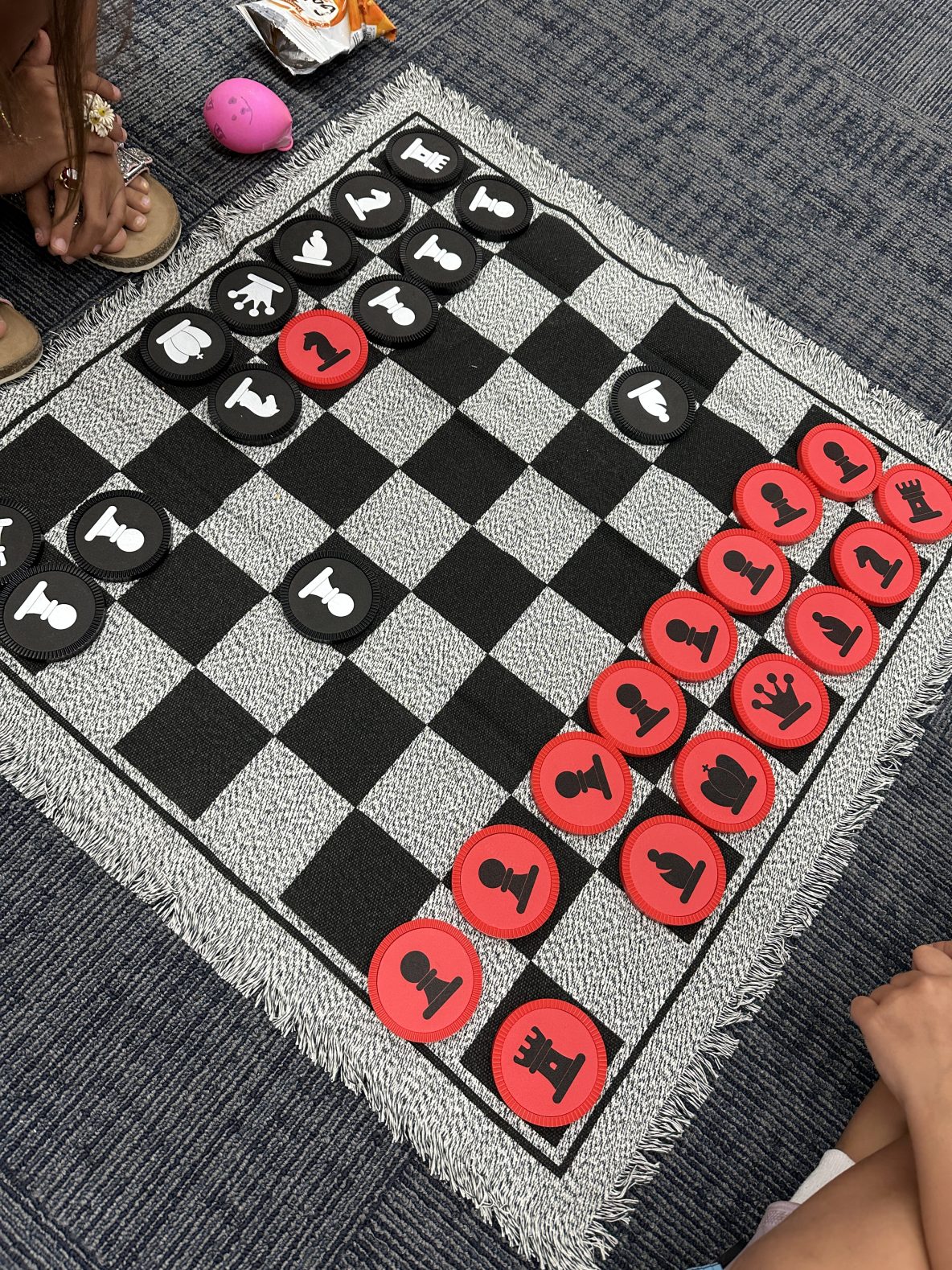 this photo is of kids playing chess on a floor mat