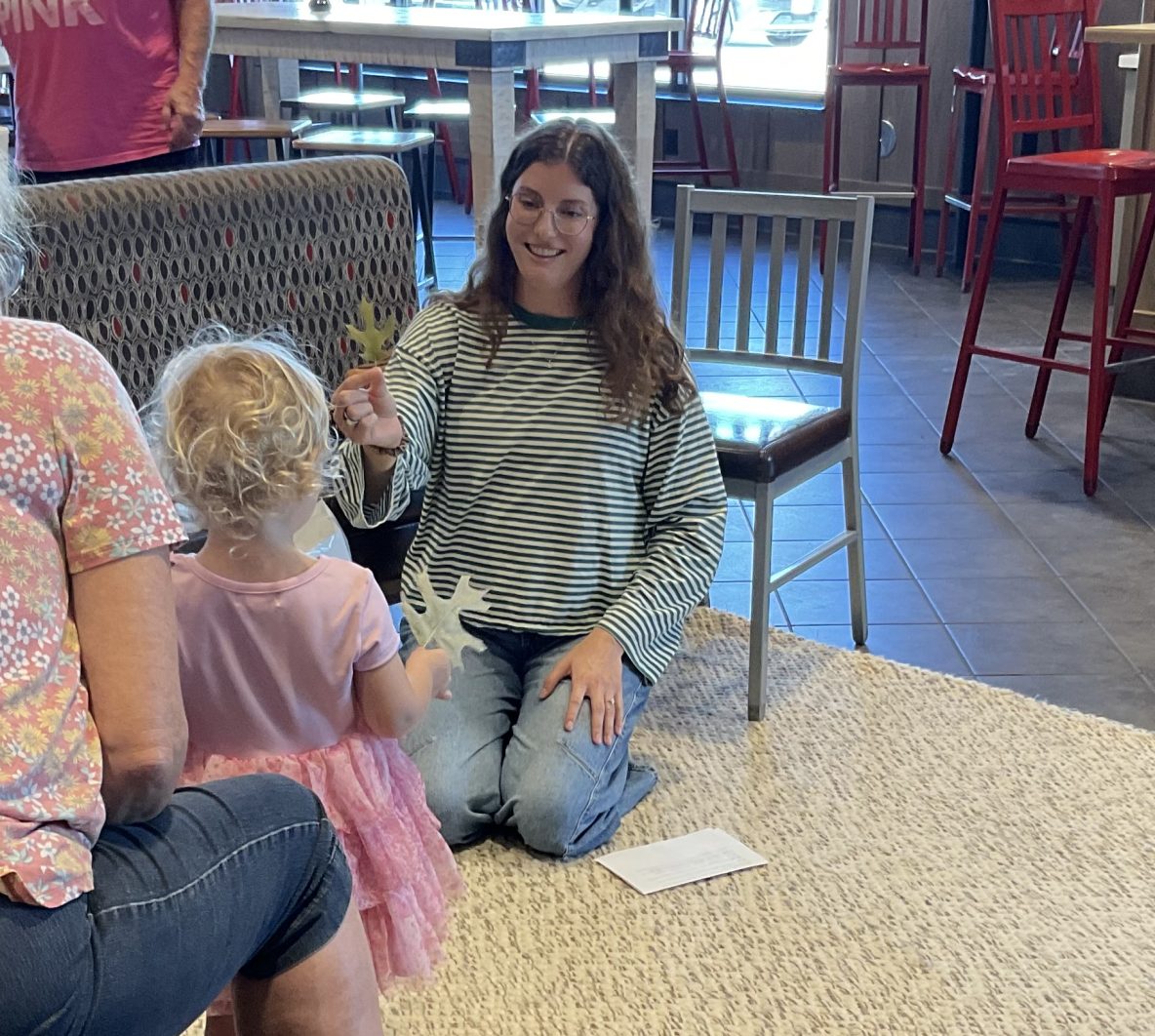 librarian and toddler hold up fall leaves